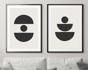 May include: Two black and white abstract geometric prints in black frames. The print on the left features a circle with a smaller circle inside and a horizontal line across the middle. The print on the right features three stacked semi-circles.
