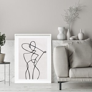 K&ouml;nnte beinhalten: Eine Schwarz-Wei&szlig;-Linienzeichnung eines menschlichen K&ouml;rpers im minimalistischen Stil. Die Zeichnung ist in einem wei&szlig;en Rahmen gerahmt und h&auml;ngt an einer Wand &uuml;ber einem Sofa.