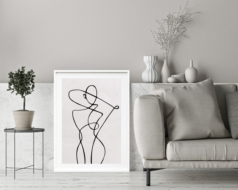 K&ouml;nnte beinhalten: Eine Schwarz-Wei&szlig;-Linienzeichnung eines menschlichen K&ouml;rpers im minimalistischen Stil. Die Zeichnung ist in einem wei&szlig;en Rahmen gerahmt und h&auml;ngt an einer Wand &uuml;ber einem Sofa.