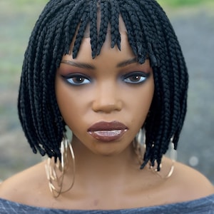 May include: A white ceramic mug with a black handle and the text "But First, Coffee" in a bold, black font. The mug is set against a blurred background, suggesting a cozy setting.