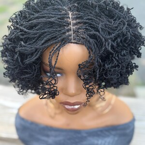 May include: A black micro-braided wig with a natural-looking hairline. The wig features small, tightly woven braids that create a textured, voluminous style. The wig is styled on a mannequin head, showcasing the intricate braiding pattern and overall aesthetic.
