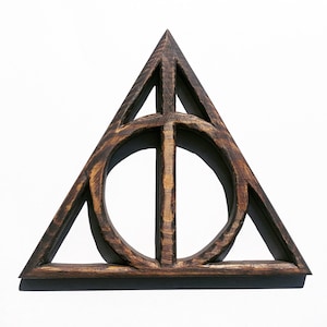May include: A dark brown wooden triangle with a circle inside. The triangle is a symbol from the Harry Potter series.