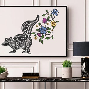 以下が含まれることがあります： 白黒の線画で描かれた、スタイリッシュなスカンクのイラスト。尻尾は花束になっており、黄色、青、紫、緑の花が咲いています。作品は額装され、白い壁に飾られています。