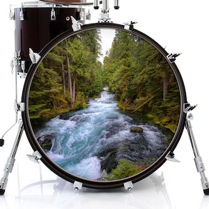 May include: A bass drum with a forest scene printed on the front. The scene features a rushing river flowing through a lush green forest.