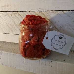 May include: A glass jar filled with red sugar scrub, labelled "Jen P Rustic Creations".