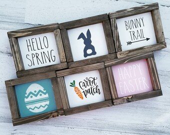 Puede incluir: Seis letreros de madera con varios diseños de temática de Pascua. Los letreros presentan frases como "Hello Spring", "Bunny Trail", "Happy Easter" y "Carrot Patch".