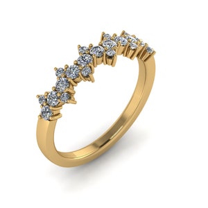 Peut inclure: Une bague dorée avec un anneau incurvé. Le dessus de la bague présente un groupe de petites pierres précieuses rondes et transparentes. Les pierres précieuses sont disposées en forme légèrement incurvée, créant un design délicat et élégant.