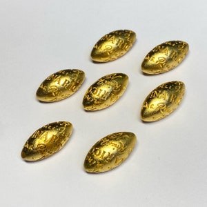 Peut inclure: Sept perles ovales de couleur dorée avec les mots "Rina Ric" en relief.