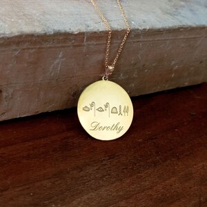 May include: Gold necklace with a round pendant featuring the name "Dorothy" engraved in cursive script and a row of ancient Egyptian hieroglyphs above the name.