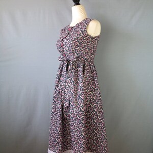 May include: A sleeveless floral print dress with a navy blue background and small pink and white flowers. The dress has a fitted bodice, a bow at the waist, and a white lace trim at the hem.