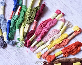 May include: A collection of embroidery floss spools in various colors, including blue, green, red, pink, yellow, orange, and brown. The spools are labeled "MYA" and have yellow labels.