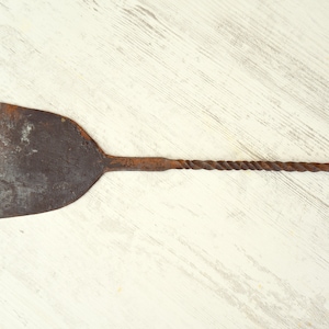 May include: A rusty metal fireplace poker with a twisted handle and a flat, rectangular head.