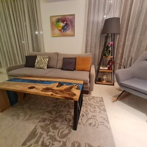 May include: A living room with a gray couch, a gray armchair, a wooden coffee table with a blue resin river, and a floor lamp with a black shade.