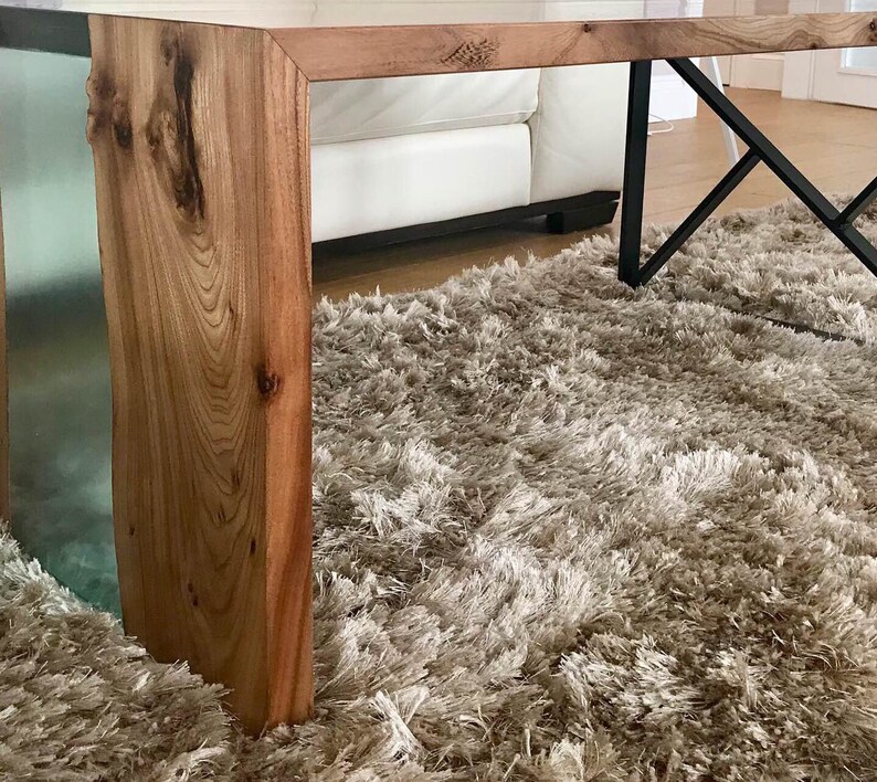 May include: A close-up of a wooden table leg with a clear epoxy resin inlay. The table leg is resting on a light brown shag rug.