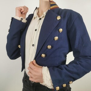 May include: A navy blue cropped jacket with gold buttons and a red and gold trim around the collar.