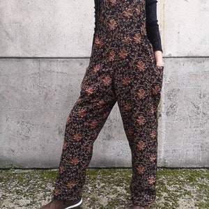 Peut inclure: Salopette noire à imprimé floral avec des jambes larges et des bretelles réglables. La salopette a une coupe ample et est fabriquée dans un tissu doux et confortable.