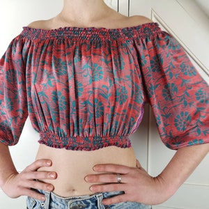 May include: A red and teal floral print off-the-shoulder crop top with elastic at the neckline and waist.