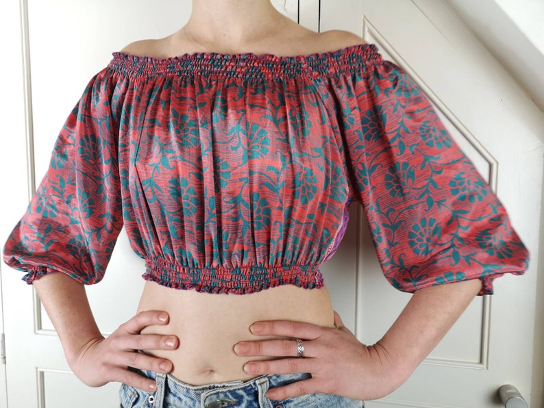 May include: A red and teal floral print off-the-shoulder crop top with elastic at the neckline and waist.