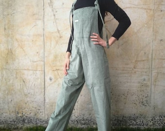 May include: A sage green corduroy jumpsuit with adjustable straps. The straps are tied at the shoulders and have a white label on the front.
