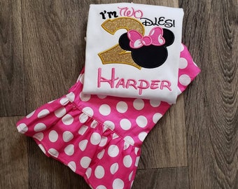 May include: A white shirt with a pink and gold number two, a pink bow, and black Mickey Mouse ears. The shirt says "I'm Two Dles!" and "Harper". The shirt is paired with a pink skirt with white polka dots.