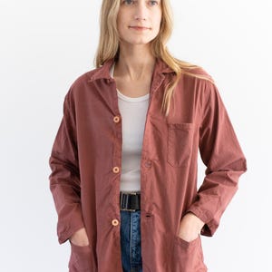 May include: A long-sleeved, rust-colored button-down shirt with a single chest pocket. The shirt is made of a soft, lightweight fabric and has a relaxed fit.