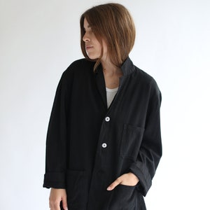 May include: A black utility jacket with a button closure and two large pockets. The jacket has a relaxed fit and is made of a soft, lightweight fabric.
