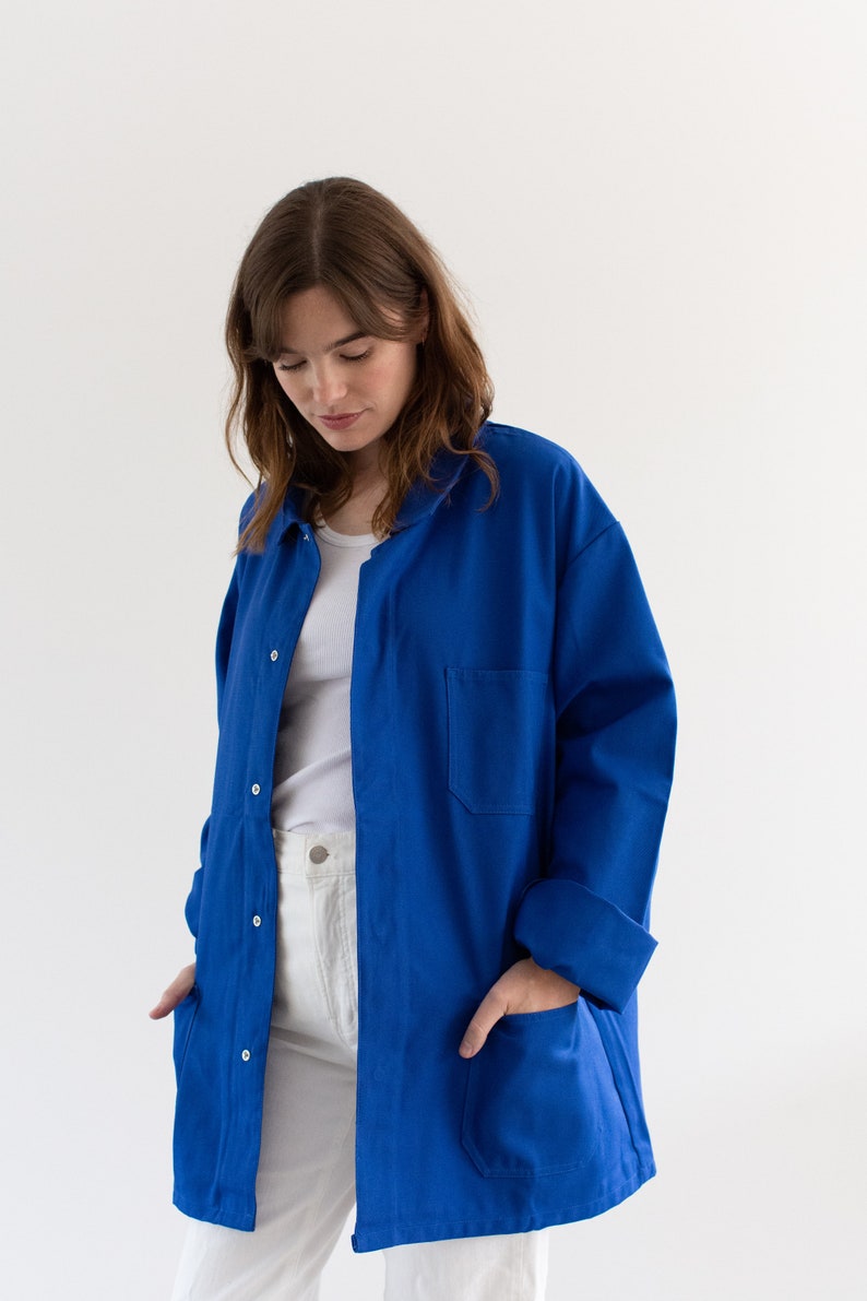 May include: A royal blue workwear jacket with a button-up front and two large pockets. The jacket is made of a durable cotton fabric and has a relaxed fit.