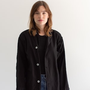 May include: A black long-sleeved shirt with a button-up front and a relaxed fit. The shirt is made of a soft, lightweight fabric and has a slightly oversized look.