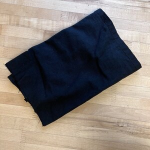 May include: A black fabric folded on a wooden surface.
