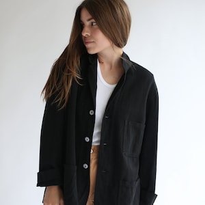 May include: A black utility jacket with a button closure and two large pockets. The jacket is made of a soft, textured fabric.