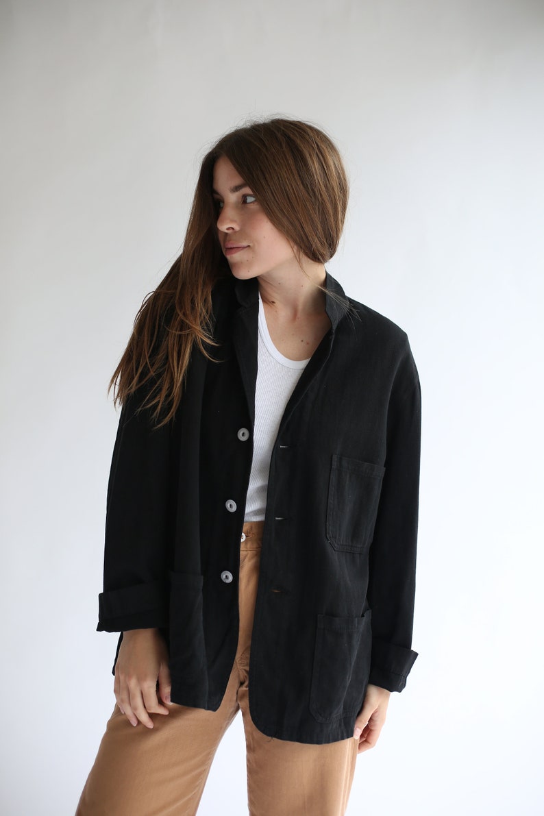 May include: A black utility jacket with a button closure and two large pockets. The jacket is made of a soft, textured fabric.