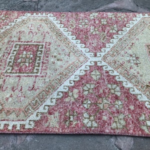 May include: A vintage pink and cream area rug with a geometric pattern. The rug has a distressed look and is made of a soft, woven material.