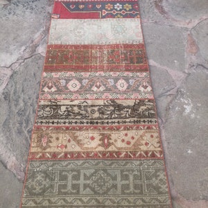 May include: A long, narrow rug with a patchwork design. The rug is made of different colored fabrics with geometric patterns. The rug is in shades of red, brown, beige, and white.
