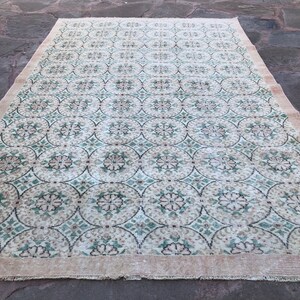 May include: A vintage rug with a cream background and a repeating pattern of green and brown floral motifs.