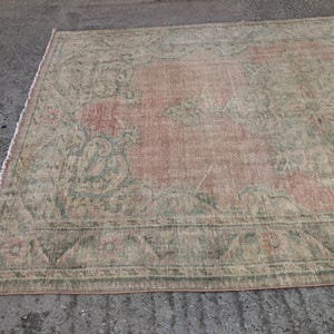 May include: A vintage rug with a faded pink and green floral pattern. The rug has a distressed look and is made of a soft, woven material.