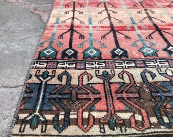 May include: A vintage rug with a colorful geometric pattern in shades of red, green, blue, and brown. The rug has a fringe border and is made of wool.
