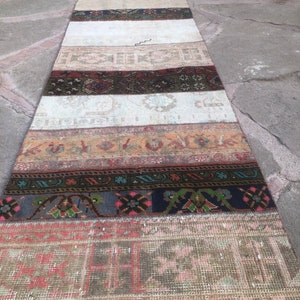 Può includere: Un tappeto lungo e stretto realizzato con diverse strisce di tessuto vintage. Il tappeto presenta un design patchwork con diversi colori e motivi, tra cui rosso, marrone, beige e blu. Il tappeto è perfetto per aggiungere un tocco di fascino vintage a qualsiasi stanza.