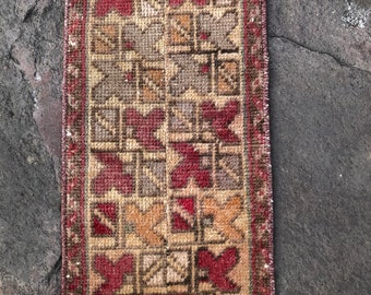 May include: A vintage runner rug with a geometric pattern in shades of red, brown, and beige. The rug has a fringe border and is made of wool.