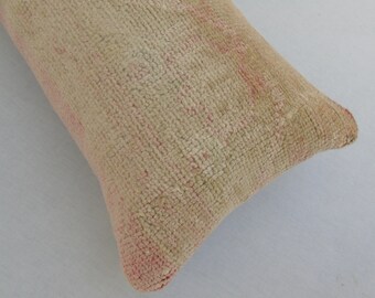 May include: A close-up of a beige and pink pillow with a textured surface. The pillow is made of a soft, woven fabric.