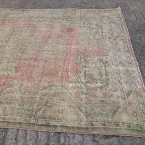 May include: A vintage rug with a faded pink and green floral pattern. The rug has a distressed look and is made of a soft, woven material.