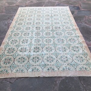 May include: A vintage rug with a cream background and a repeating pattern of green and brown circles and floral designs.
