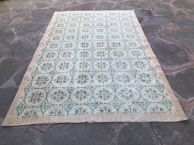 May include: A vintage rug with a cream background and a repeating pattern of green and brown circles and floral designs.