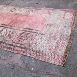 May include: A vintage pink and cream rug with a floral pattern and fringe edges.