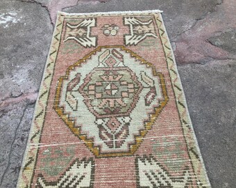 May include: A vintage Turkish runner rug with a pink background and a central medallion design in shades of beige, brown, and green. The rug has a fringed edge.