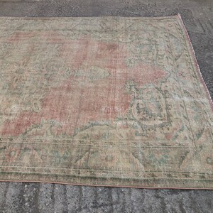 May include: A vintage rug with a faded pink and green floral pattern. The rug has a distressed look and is made of a soft, woven material.