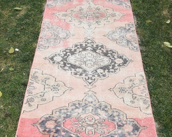 May include: A pink and cream runner rug with a traditional Persian design in black. The rug has a faded, vintage look and is perfect for adding a touch of bohemian style to your home.