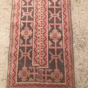May include: A long, narrow rug with a dark brown background and a pink and gray geometric pattern. The rug has a fringe border. color on images may slight be different from the real rug