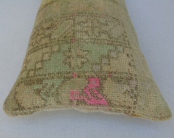 May include: A beige and green patterned pillow with pink accents. The pillow is made of a soft, woven fabric and has a slightly distressed look.