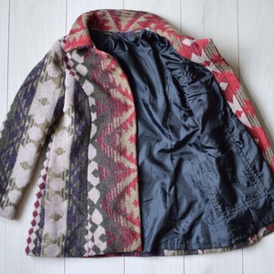 May include: A long-sleeved coat with a geometric pattern in shades of red, green, brown, and purple. The coat is lined with black fabric.