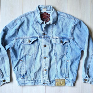 Könnte beinhalten: Hellblaue Jeansjacke mit Knopfleiste, zwei Brusttaschen und einem Markenetikett auf der rechten unteren Seite.